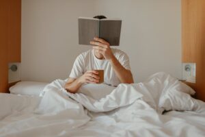 Person reading a book in bed as part of a nightly routine, representing how to create a habit loop that actually sticks and reinforces consistency and focus.