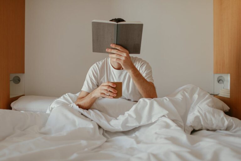 Person reading a book in bed as part of a nightly routine, representing how to create a habit loop that actually sticks and reinforces consistency and focus.